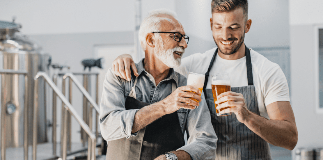 Older and younger man cheers with a beer